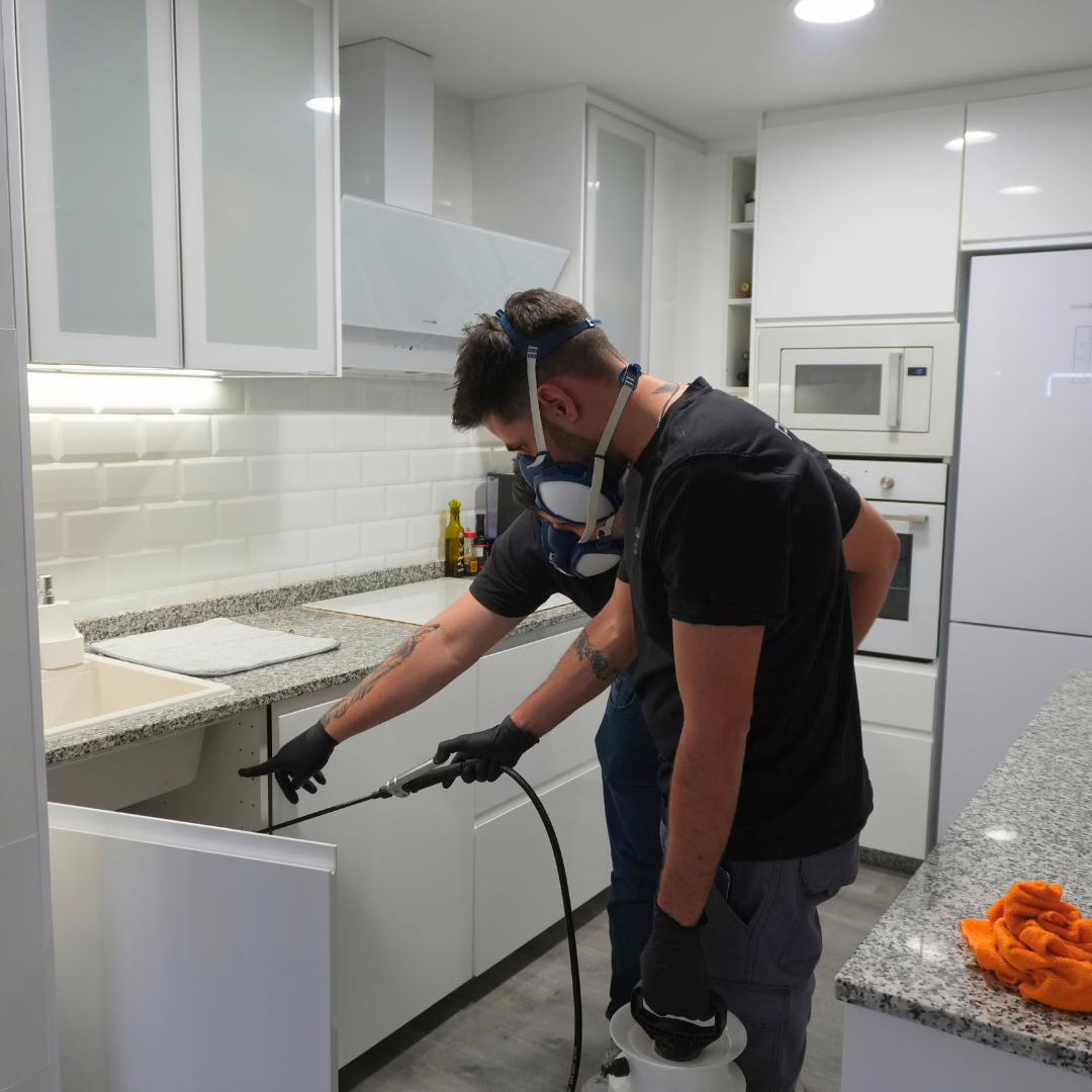 Técnico de Plaguisa aplicando tratamiento contra cucarachas bajo muebles de cocina